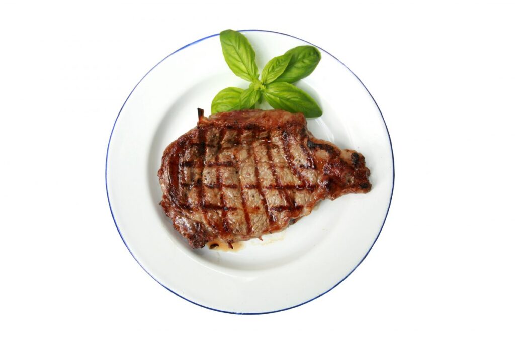 A cooked steak on a white plate.